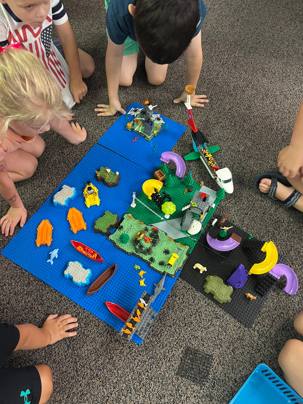 Children gathered around a large LEGO build on the floor