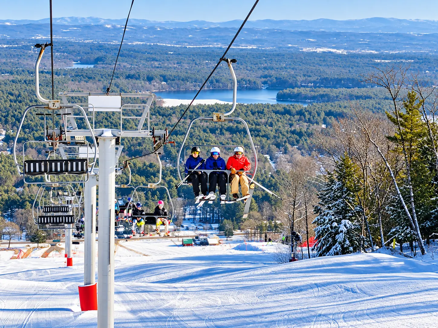 Skiers riding the West Mountain chairlift with a sweeping view of the lake and mountains